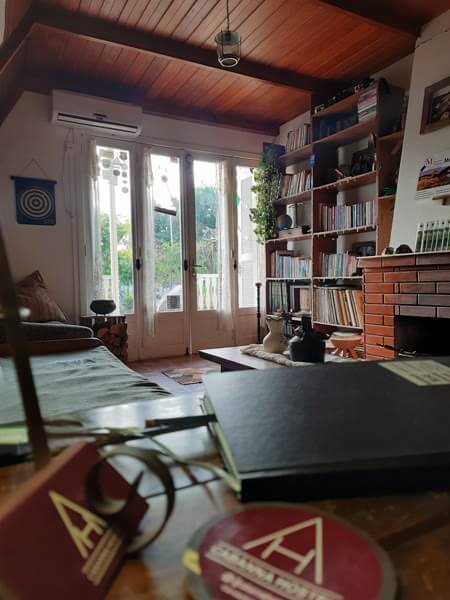 Sala comum rústica com estante de livros, lareira e vista para o jardim