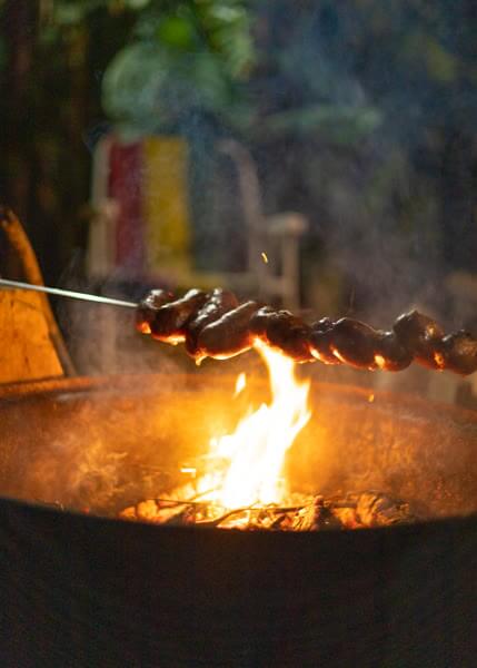 Linguiças grelhadas na brasa da fogueira à noite