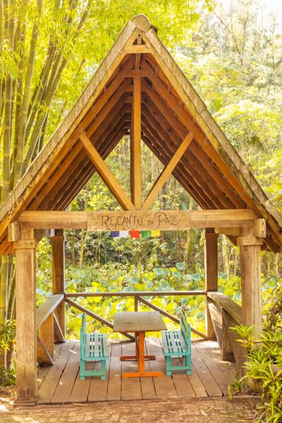 Gazebo Recanto da Paz com mesa e bancos em jardim arborizado