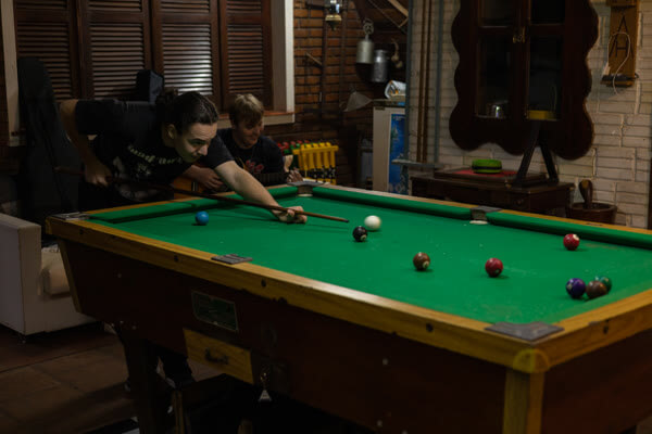 Hóspedes jogando sinuca e tocando violão na sala de lazer