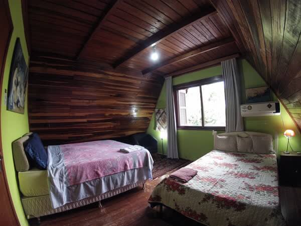 Quarto rústico com paredes verdes, painéis de madeira e duas camas