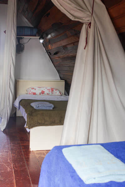 Nicho privativo para dormir com cortinas e cama de solteiro em cabana de madeira