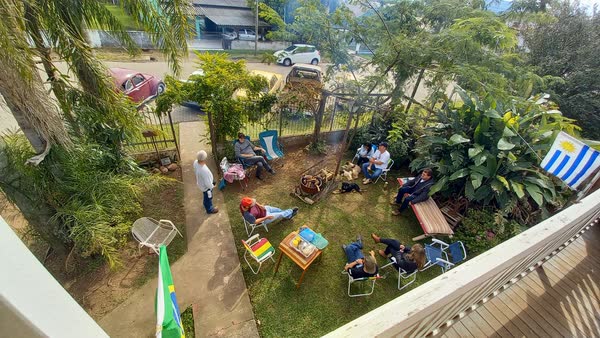 Hóspedes reunidos no jardim ao redor de uma fogueira com bandeiras do Brasil e do Uruguai