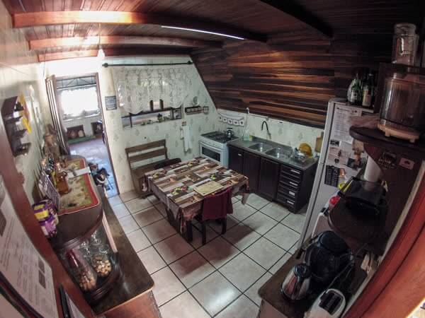 Cozinha e área de refeições rústicas com teto de madeira e paredes de azulejo